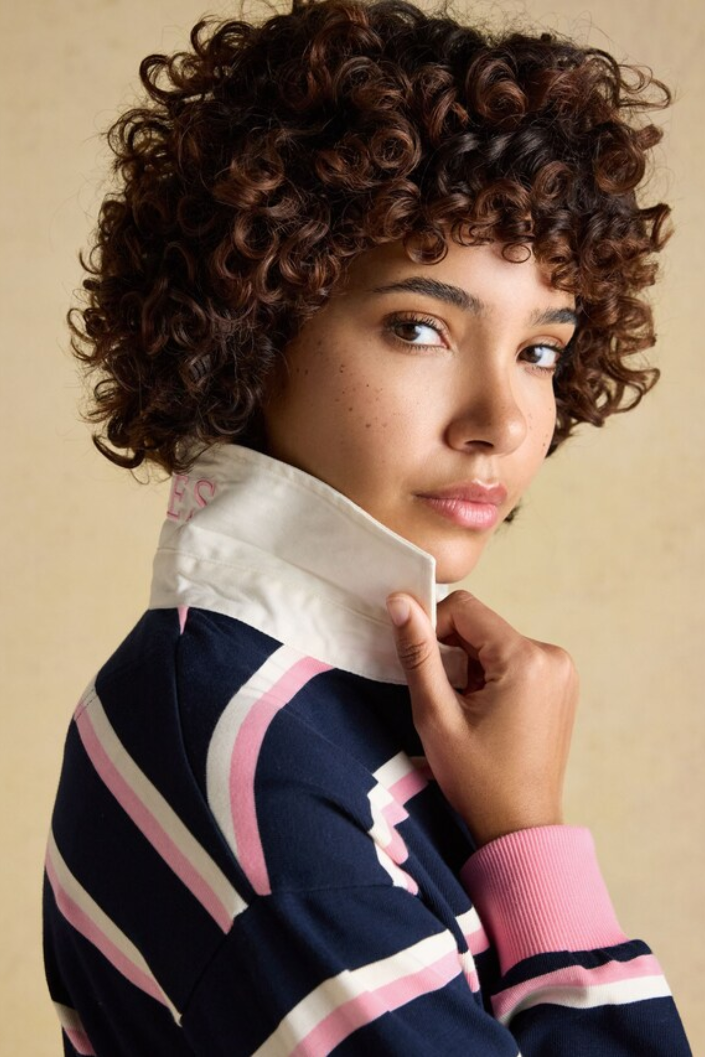 Woman with curly hair wearing Joules W30854 Lara Rugby Shirt – Navy / Pink Stripe by Joules shop Dotique