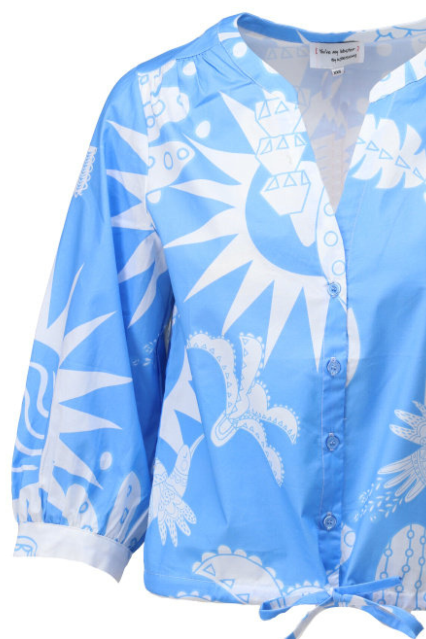 Blue blouse with white abstract sunburst and geometric shapes, button front and tie detail at hem