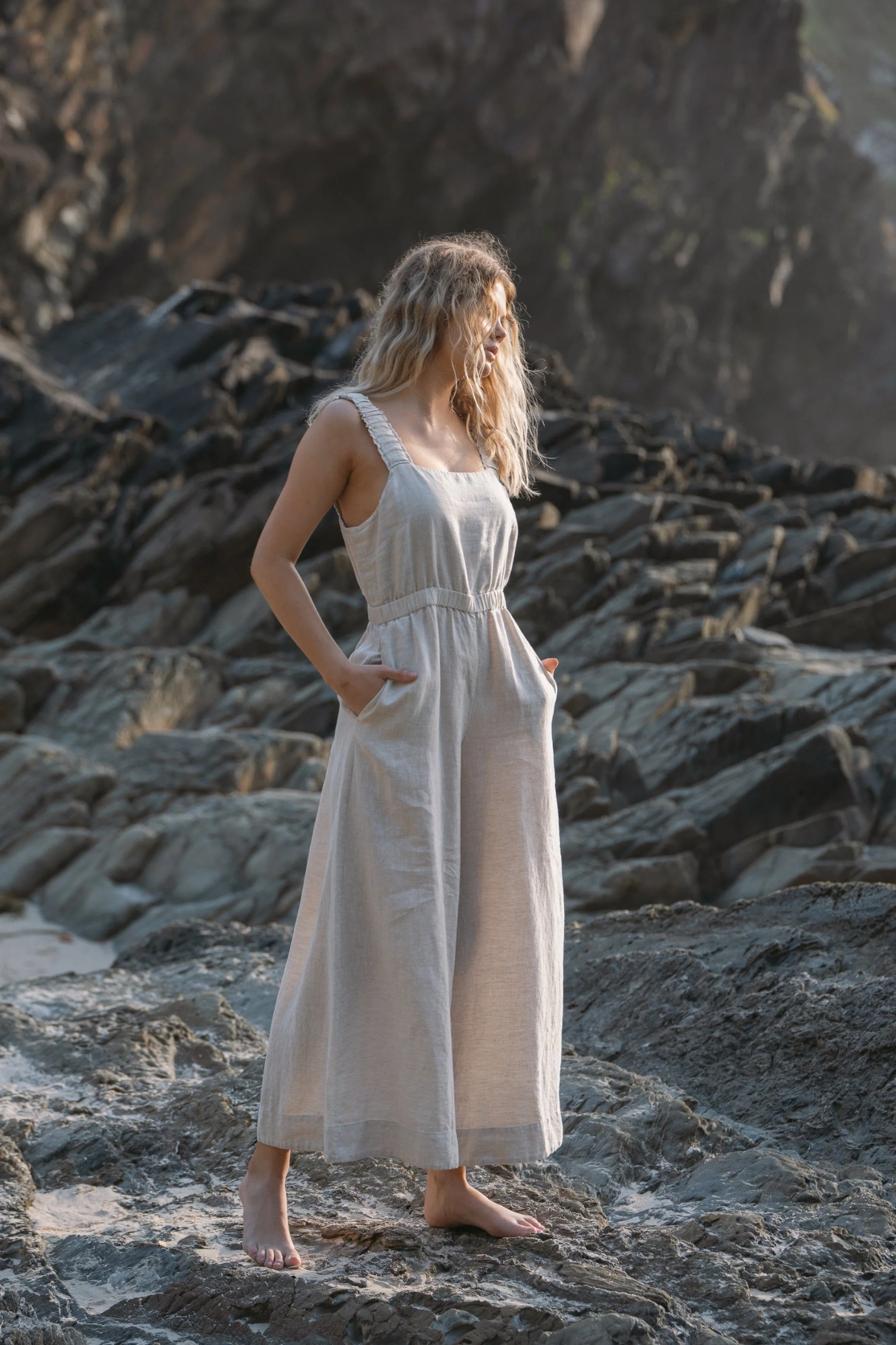 Woman standing on rocks wearing Lilly Pilly LPS23-D004 Keely Linen Jumpsuit Oatmeal by Lilly Pilly Shop at Dotique