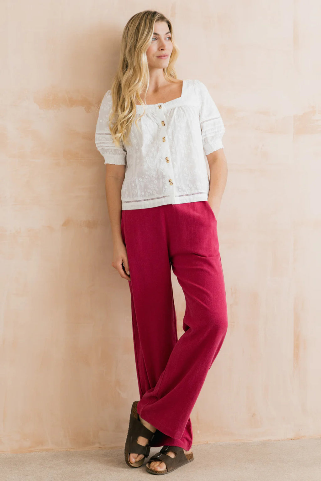 Lily & Me LM26137 Poppy Blouse Plain Stripe Dobby White worn by model with pink wide-leg pants, featuring button details and textured fabric by Lily & me. Shop Lily & me at Dotique.