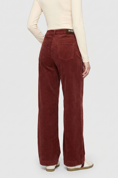 Back view of a model wearing burgundy wide-leg corduroy pants with a cream long-sleeve top and sandals