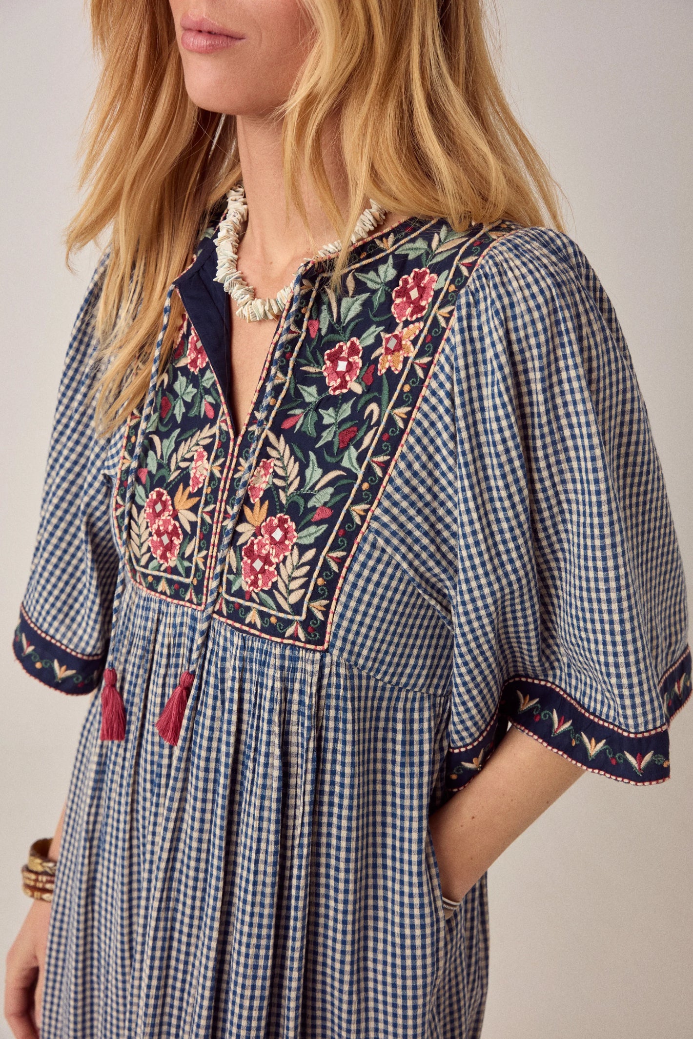 Close-up of model wearing Maison Hotel Augusta Dress Bleu Picnic with floral embroidery and check pattern Shop Maison Hotel at Dotique