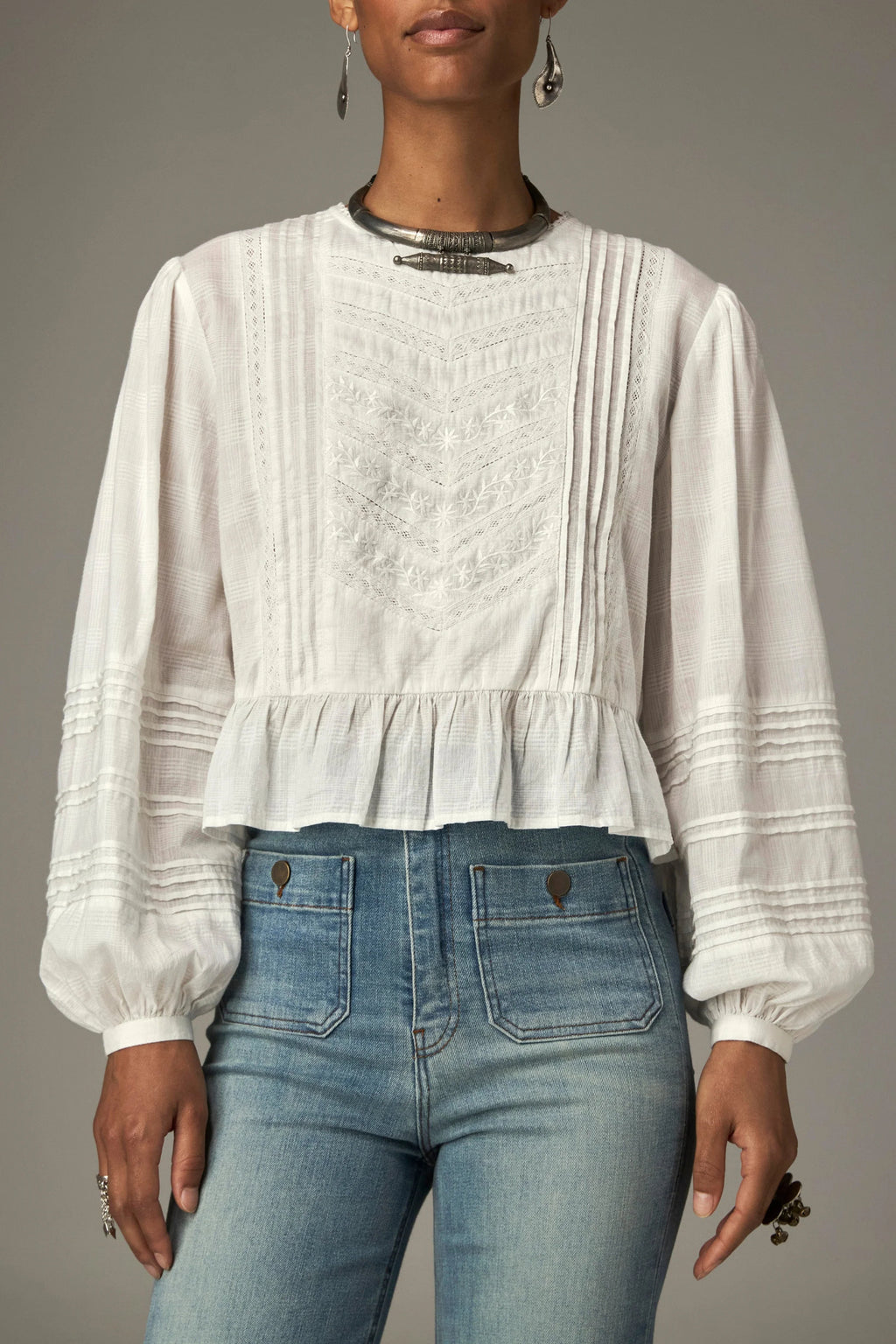 Shop the Maison Hotel Mildred Blouse in Bone at Dotique. A cropped cotton blouse with pintuck detailing, lace-trim neckline and a pretty ruffled hem.