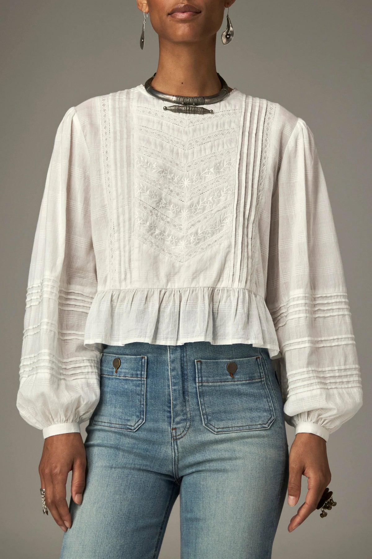 Shop the Maison Hotel Mildred Blouse in Bone at Dotique. A cropped cotton blouse with pintuck detailing, lace-trim neckline and a pretty ruffled hem.