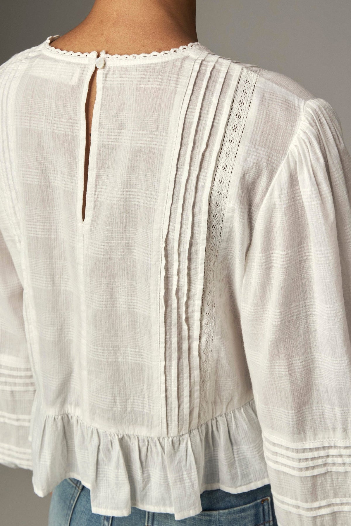 Shop the Maison Hotel Mildred Blouse in Bone at Dotique. A cropped cotton blouse with pintuck detailing, lace-trim neckline and a pretty ruffled hem.