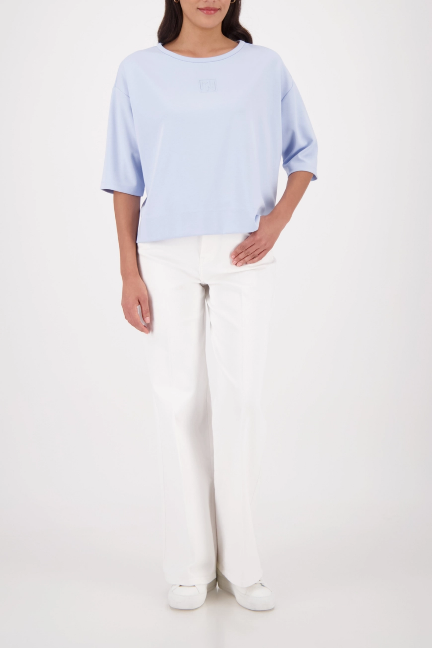 Monari 410185 Pale Blue Embossed Emblem Sweatshirt worn by model styled with white trousers Shop Monari at Dotique
