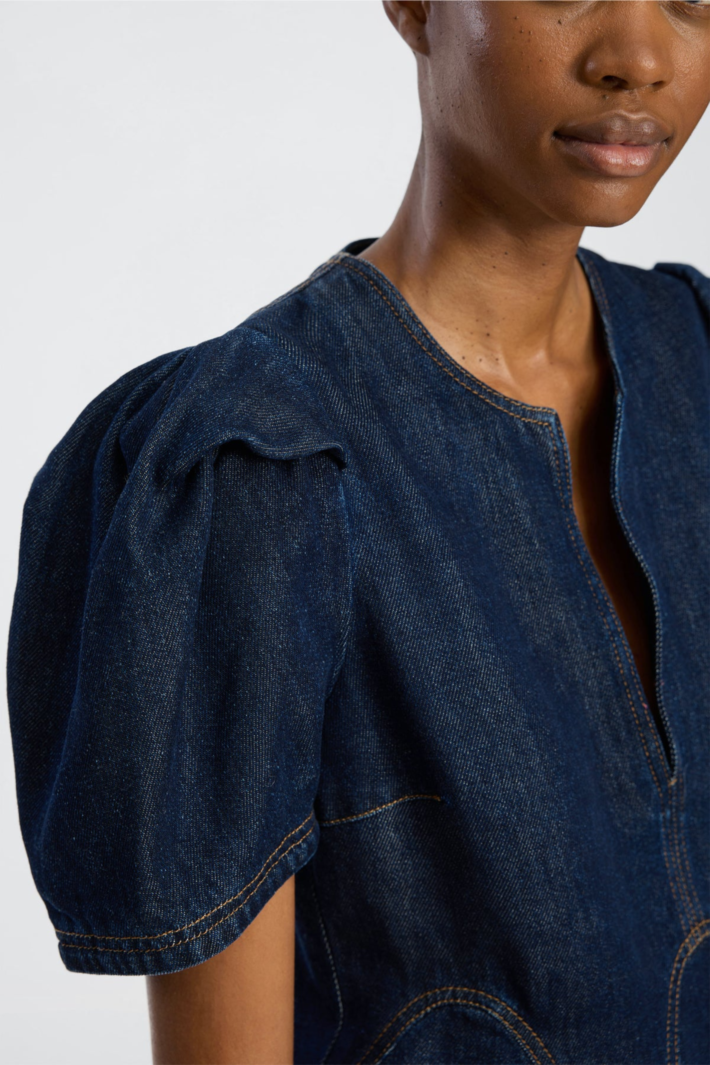 Shop the MUNTHE Baynor Top in Indigo at Dotique. Crafted from 100% TENCEL™ with contrast stitching, puff sleeves and a flattering A-line silhouette.