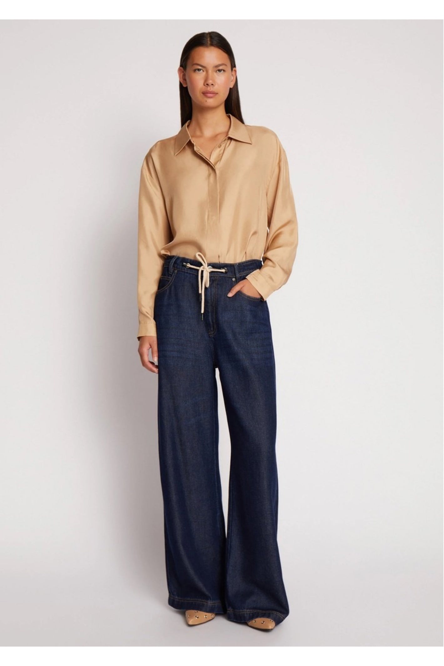 Model wearing the MUNTHE Obey Wide Leg Trousers in Indigo with a relaxed fit, tie waist and flowing wide-leg silhouette. Shop Munthe at Dotique.