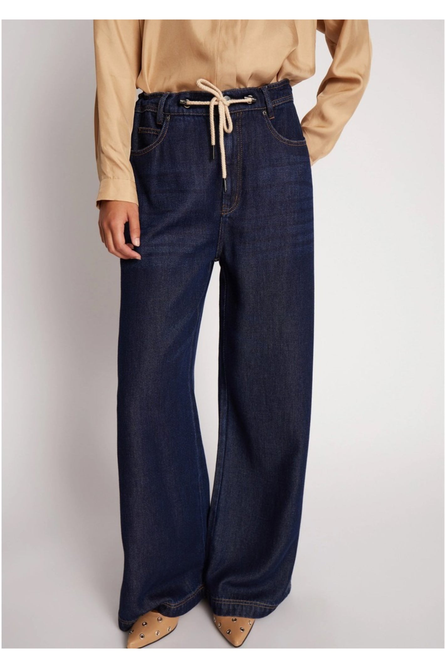 Model wearing the MUNTHE Obey Wide Leg Trousers in Indigo with a relaxed fit, tie waist and flowing wide-leg silhouette. Shop Munthe at Dotique.