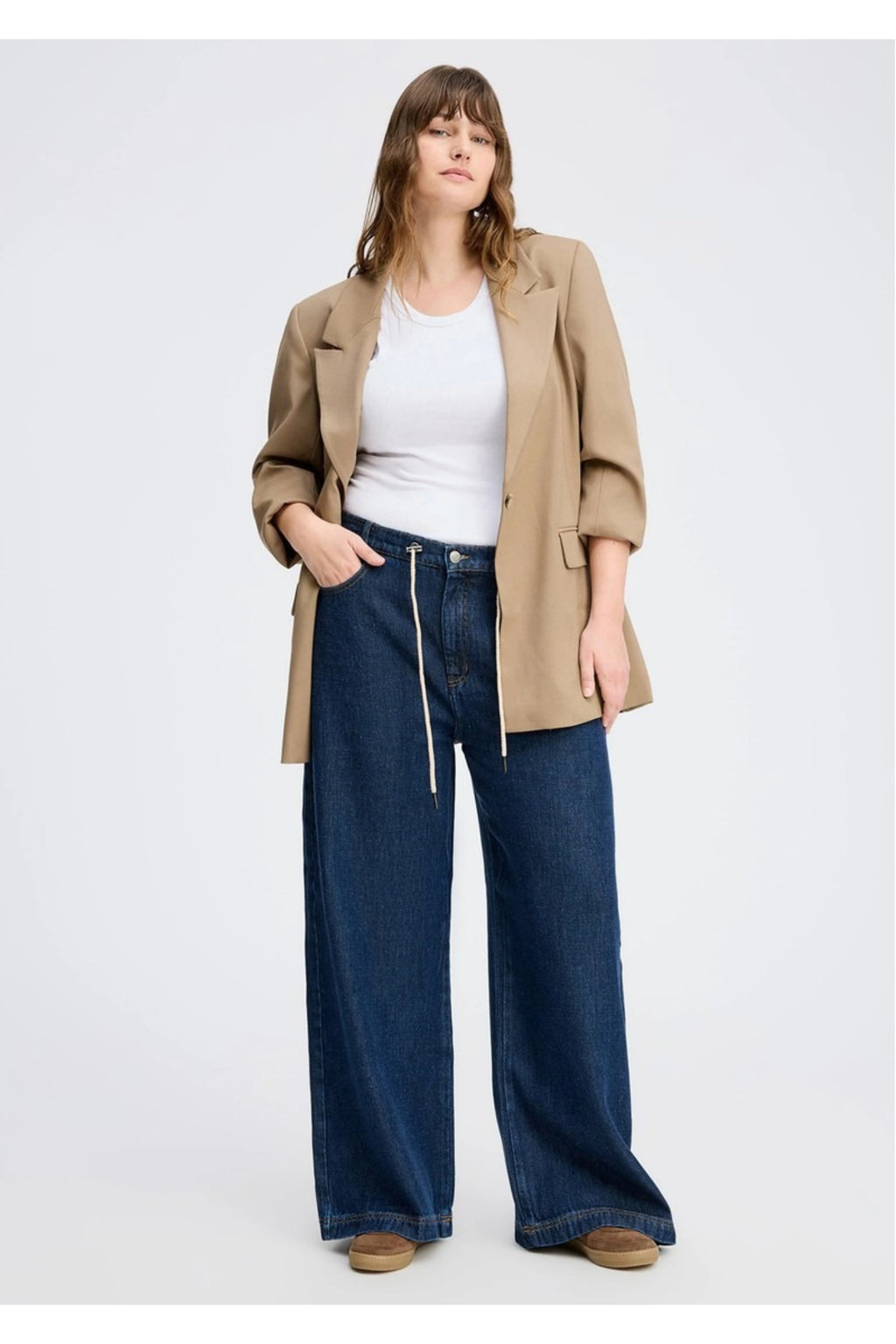 Model wearing the MUNTHE Obey Wide Leg Trousers in Indigo with a relaxed fit, tie waist and flowing wide-leg silhouette. Shop Munthe at Dotique.