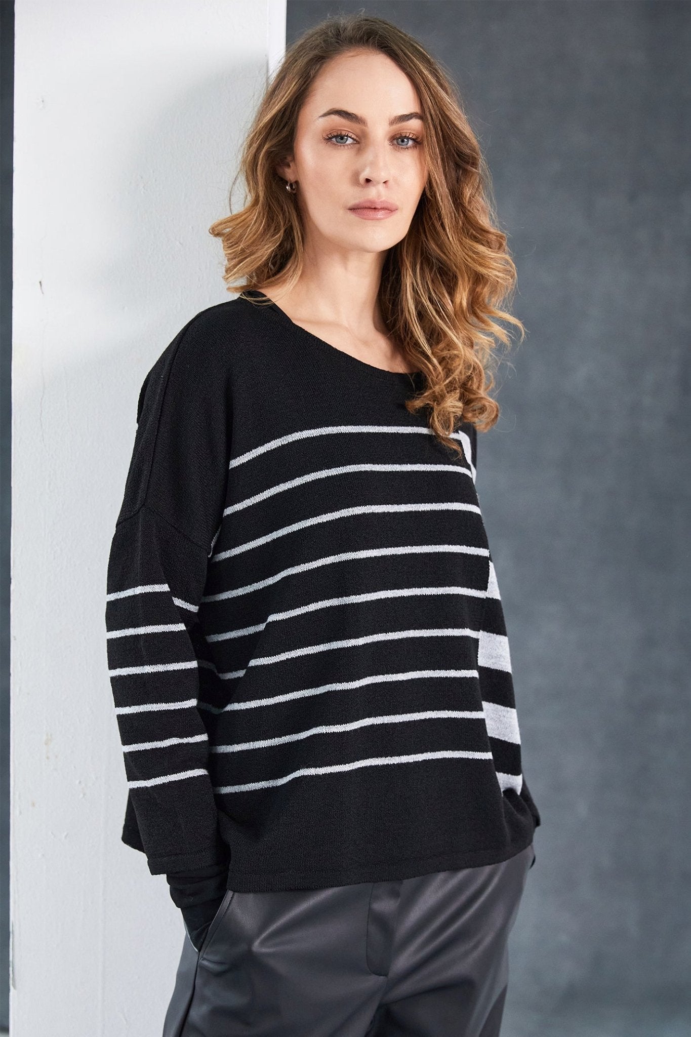 Woman wearing a black and white striped sweater against a gray background
