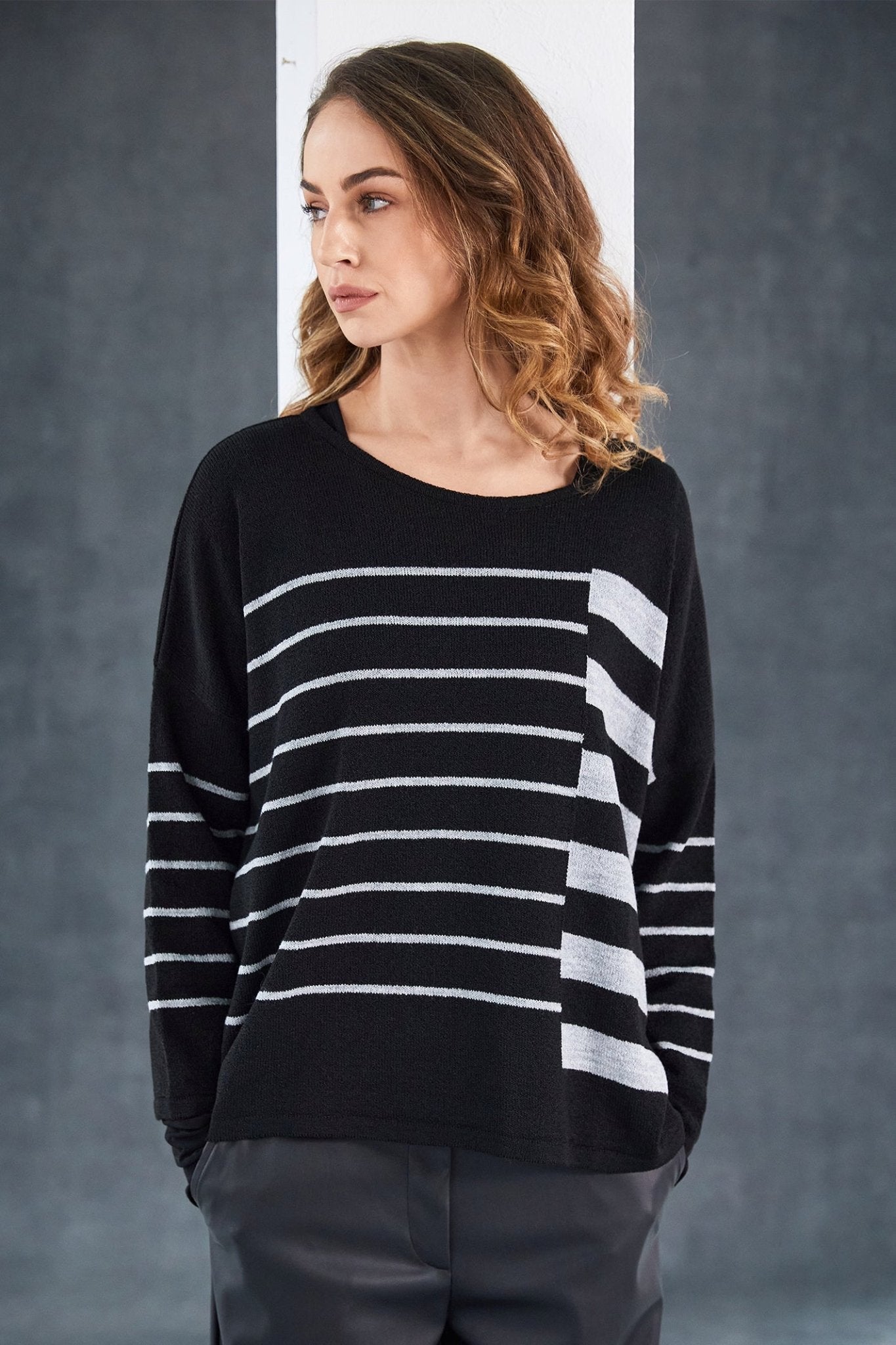 Woman wearing a black and white striped sweater against a gray background