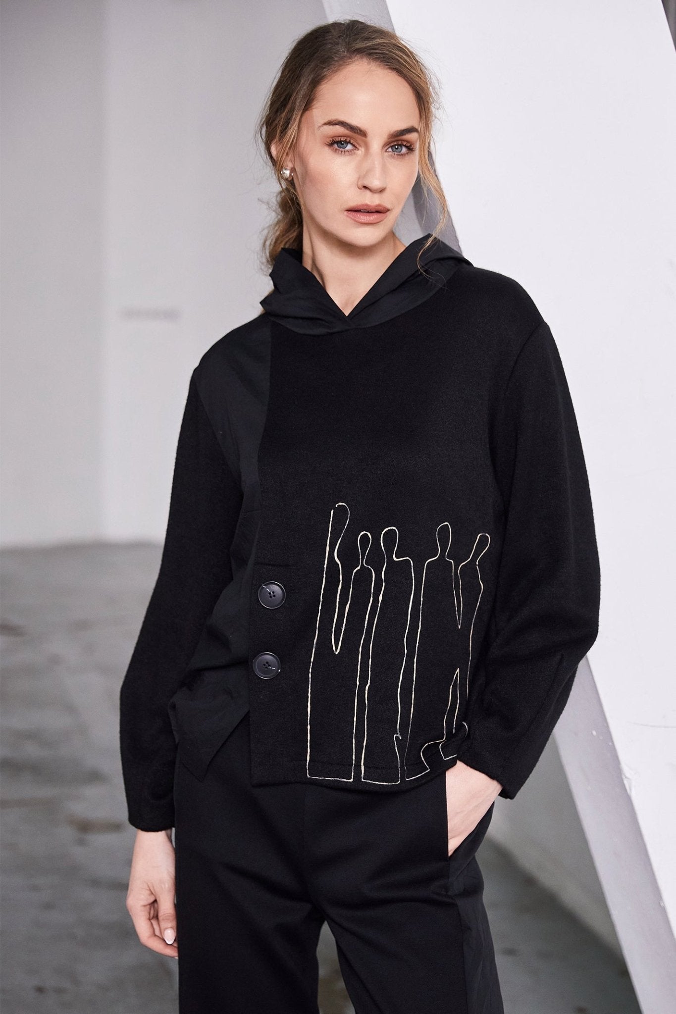 Person wearing a black outfit with a unique design on a plain background