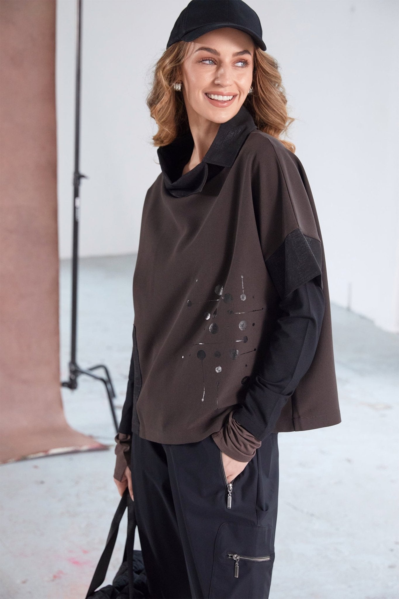 Woman wearing a brown jacket and black pants in an indoor setting