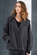 Woman wearing a gray textured jacket against a gray background