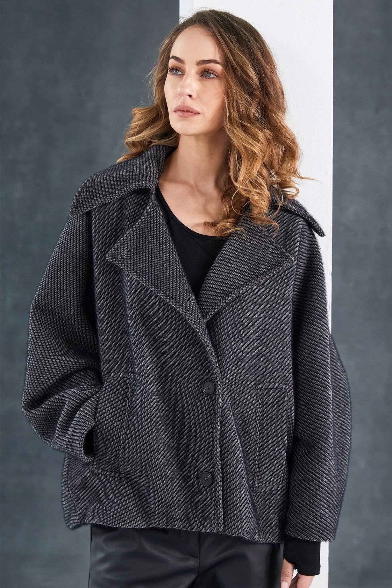 Woman wearing a gray textured jacket against a gray background