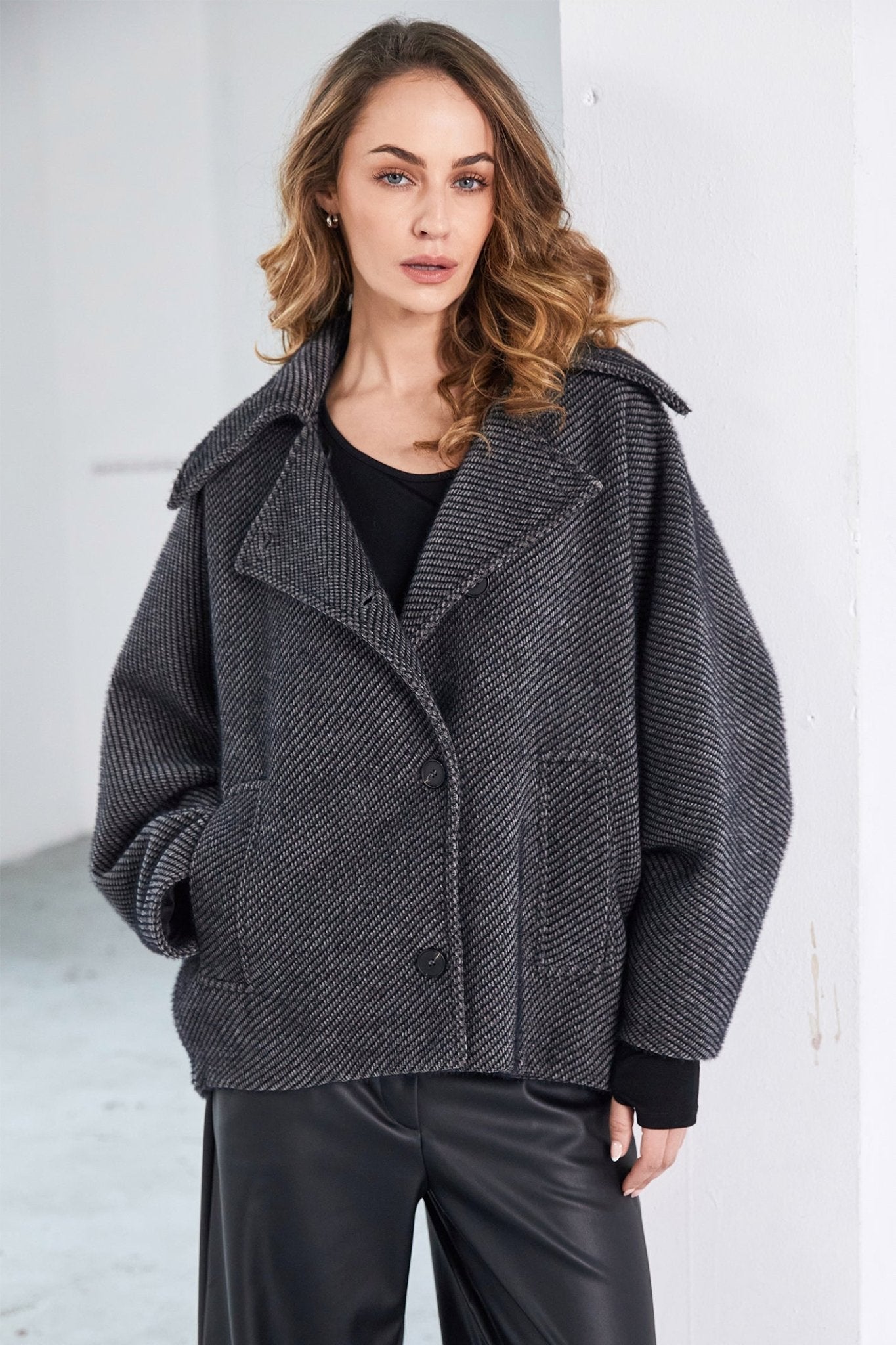 Woman wearing a gray textured coat against a white background