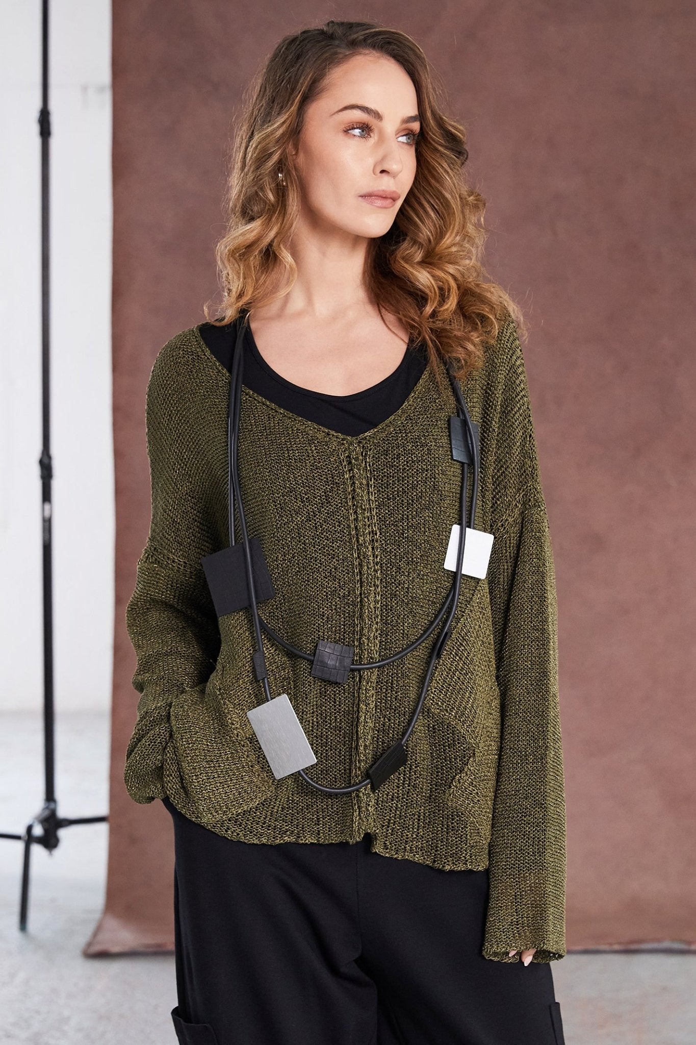 Woman wearing a green sweater with black accents against a brown background