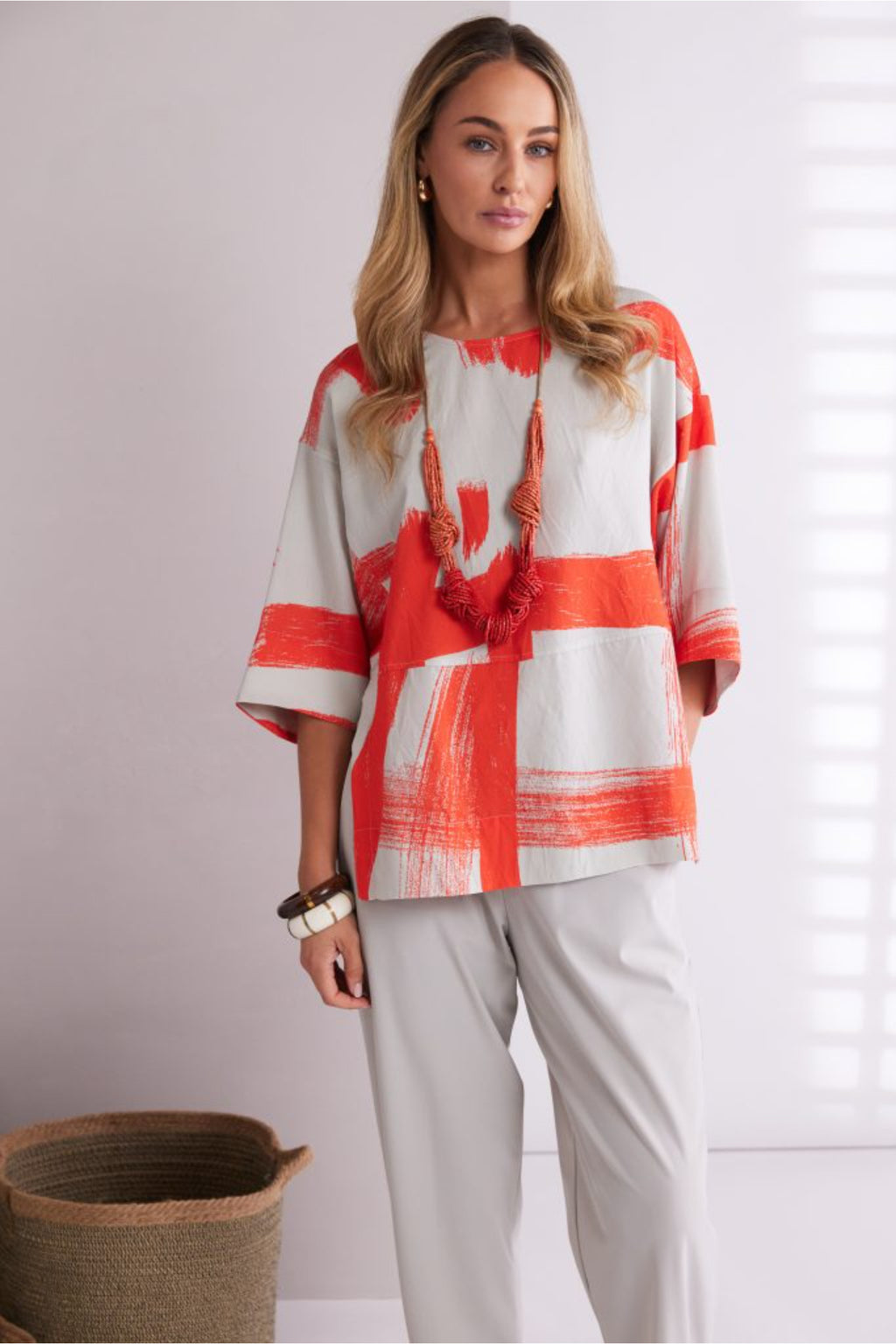 NAYA paintwork print top in coral and ivory featuring an abstract brushstroke design, round neckline, deep cuffed short sleeves and a relaxed fit with a shaped hemline. Shop at Dotique Chesterfield.