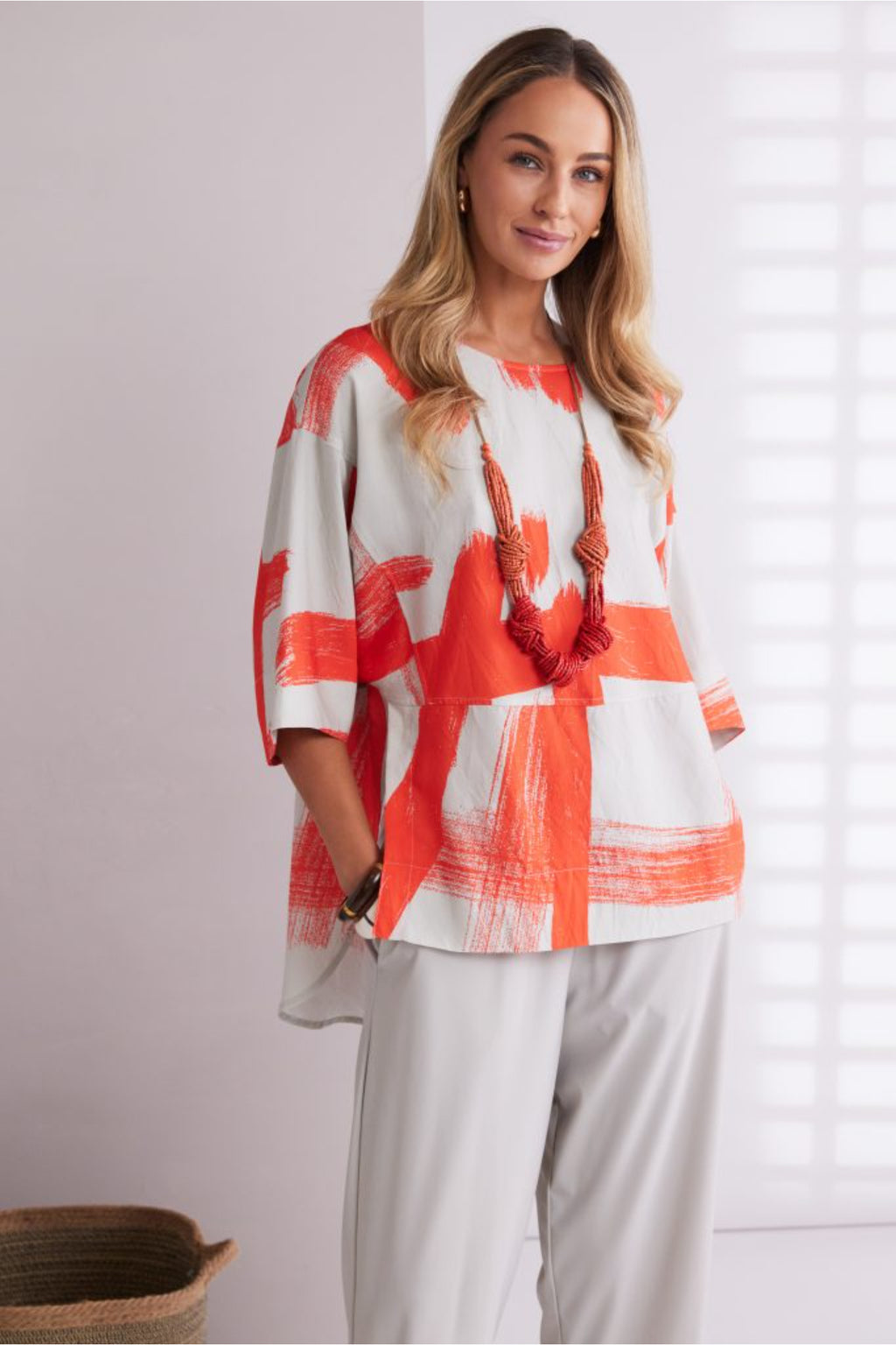 NAYA paintwork print top in coral and ivory featuring an abstract brushstroke design, round neckline, deep cuffed short sleeves and a relaxed fit with a shaped hemline. Shop at Dotique Chesterfield.