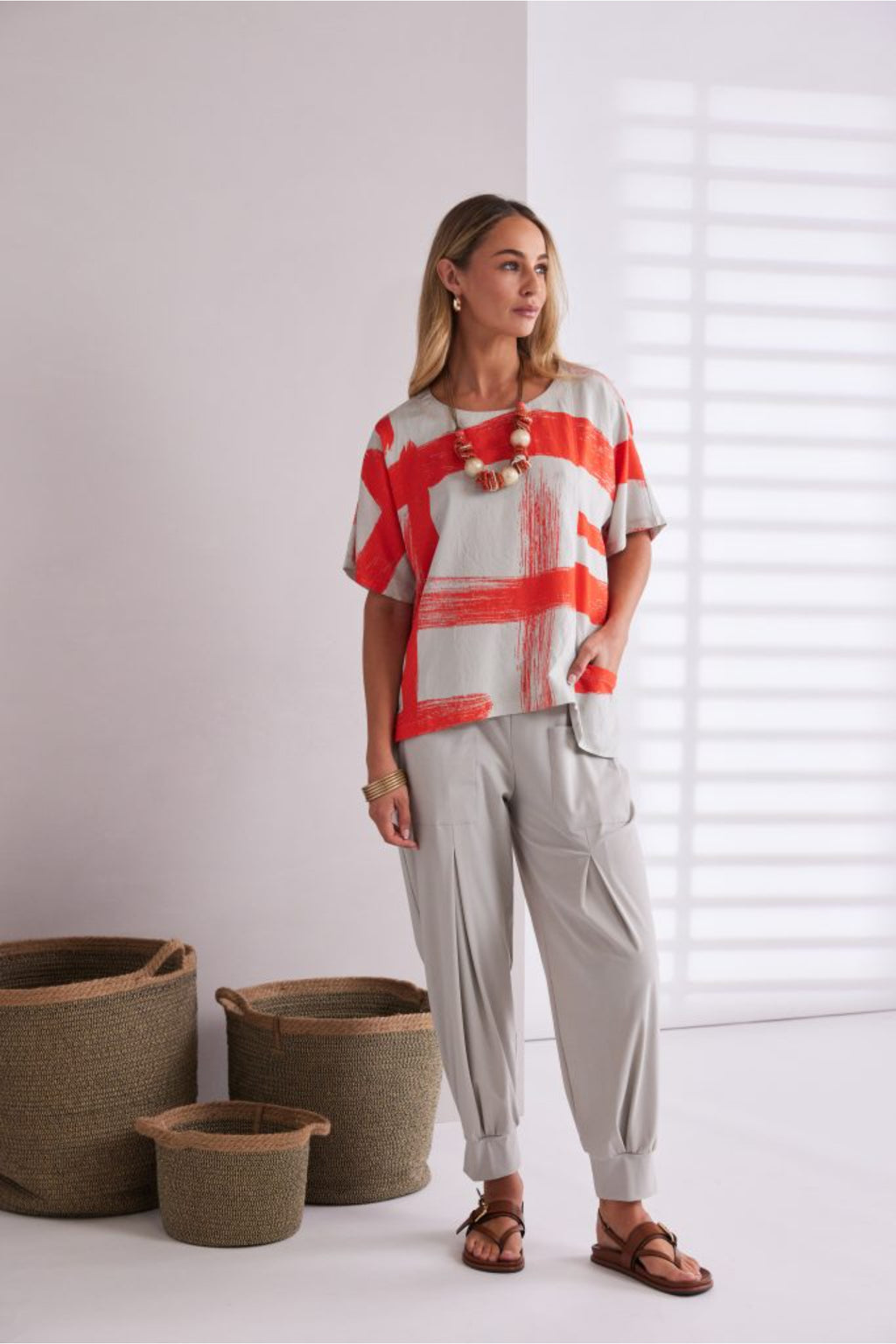 NAYA paintwork print top in coral and ivory featuring an abstract brushstroke design, round neckline, deep cuffed short sleeves and a relaxed fit with a shaped hemline. Shop at Dotique Chesterfield.