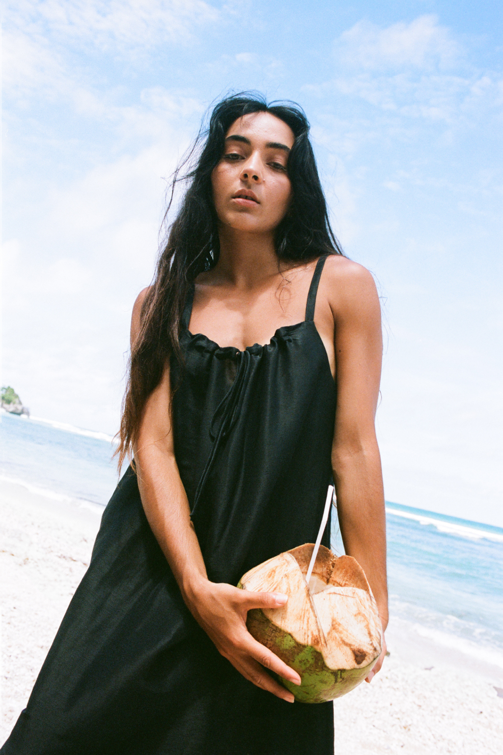 Lilly Pilly LP-D004 Nova Linen Silk Dress Black worn on beach by model holding coconut Shop Lilly Pilly at Dotique