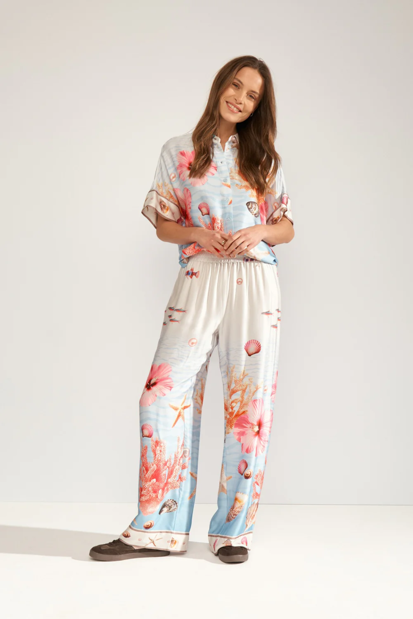 Model wearing Numph 707149 Nuoceana Wide Leg Trousers – Skyway with vibrant coral and shell prints by Numph, shop Numph at Dotique.