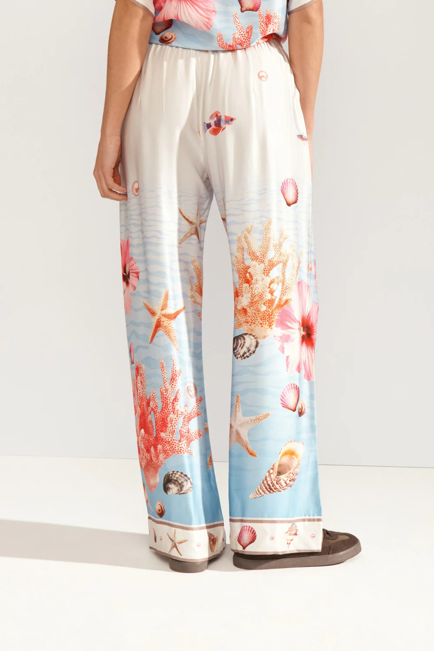 Back view of a model wearing Numph 707149 Nuoceana Wide Leg Trousers – Skyway in a sea-inspired print by Numph, shop Numph at Dotique.
