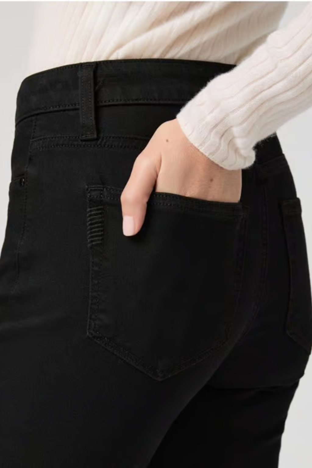 Close-up of a woman wearing PAIGE Cindy High Rise Straight Ankle Jeans Black Shadow with her hand in the back pocket by PAIGE. Shop PAIGE at Dotique.