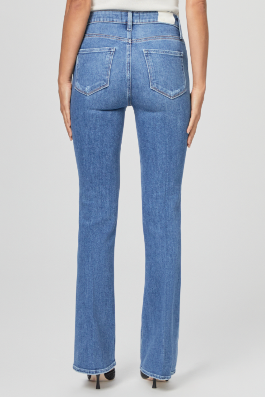 Back view of a model wearing PAIGE Laurel Canyon High Rise Bootcut Jeans Rock Show Distressed in blue denim by PAIGE. Shop PAIGE at Dotique.