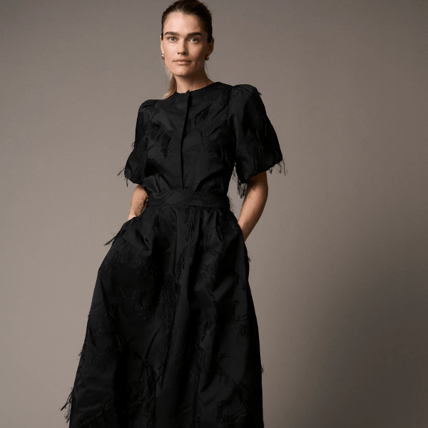 Woman wearing a black dress with puffed sleeves against a plain background