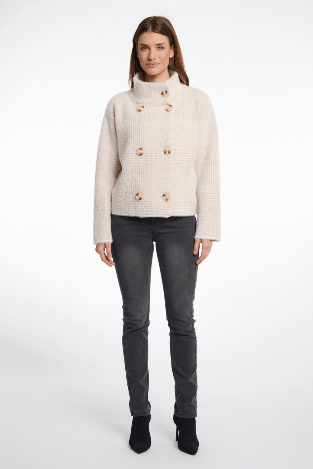 Woman wearing a cream knitted cardigan with gold buttons on a white background