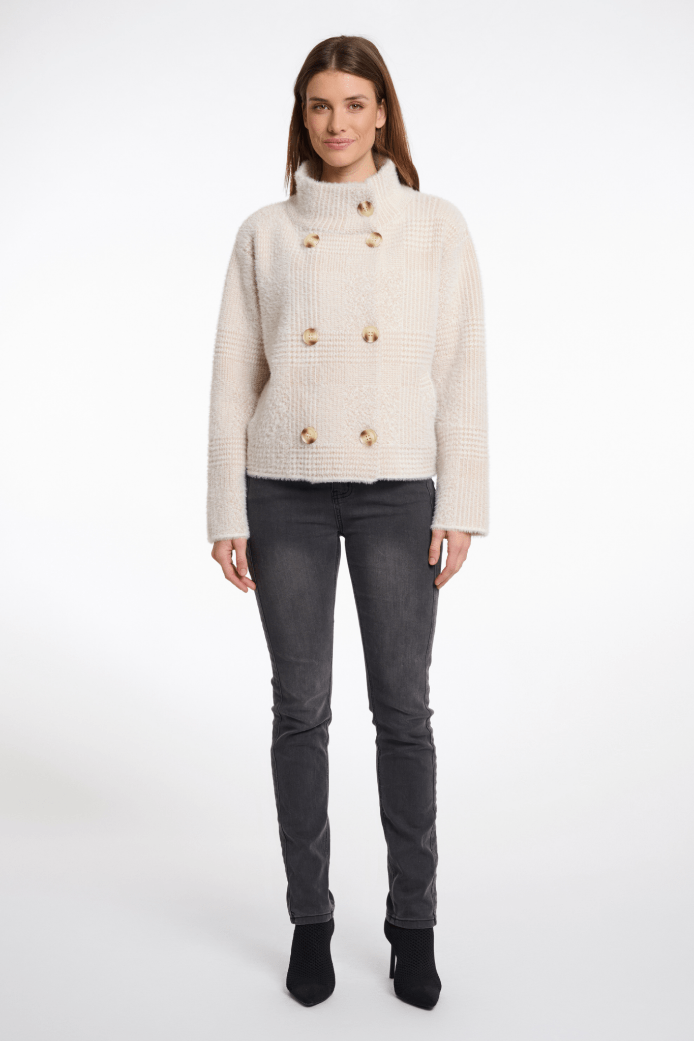 Woman wearing a cream knitted cardigan with gold buttons on a white background