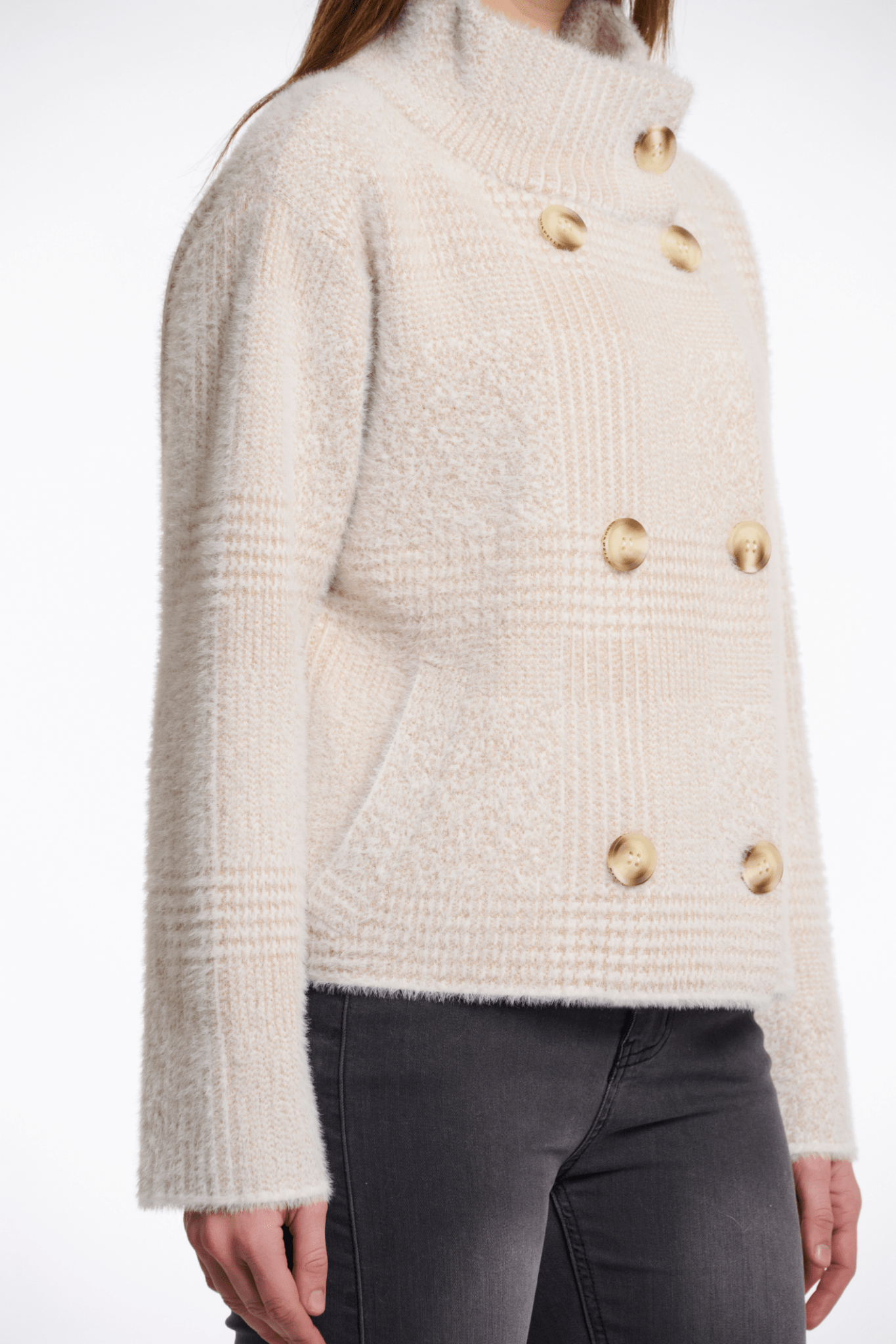 Beige knitted sweater with gold buttons worn by a person on a white background