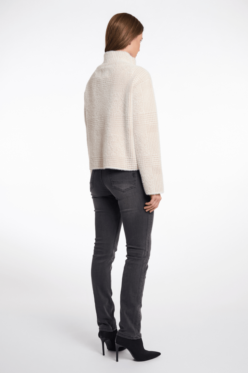 Woman wearing a white sweater and gray jeans on a white background