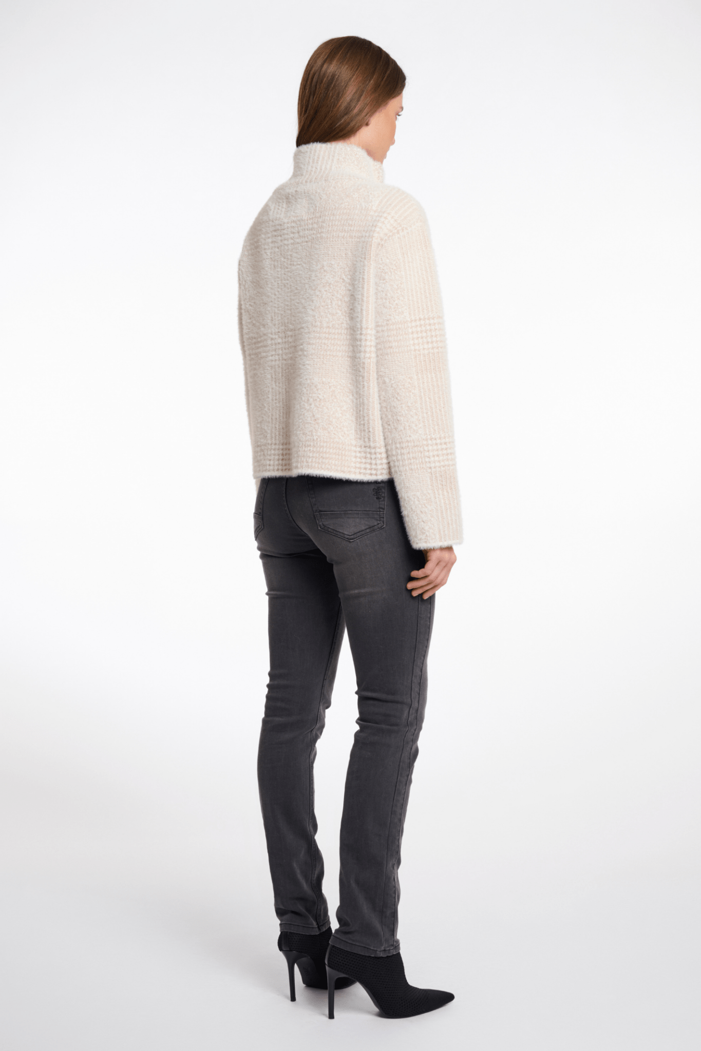 Woman wearing a white sweater and gray jeans on a white background