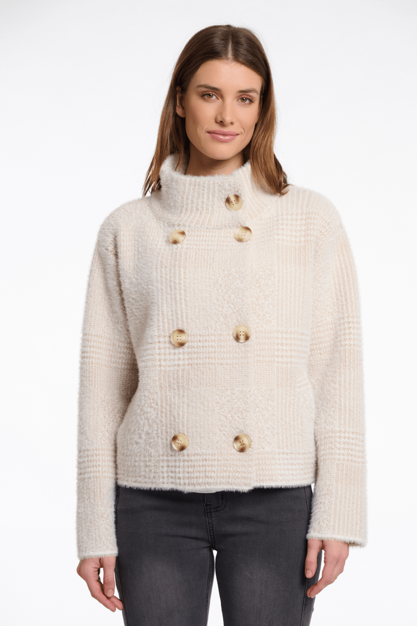 Woman wearing a cream-colored sweater with gold buttons on a white background