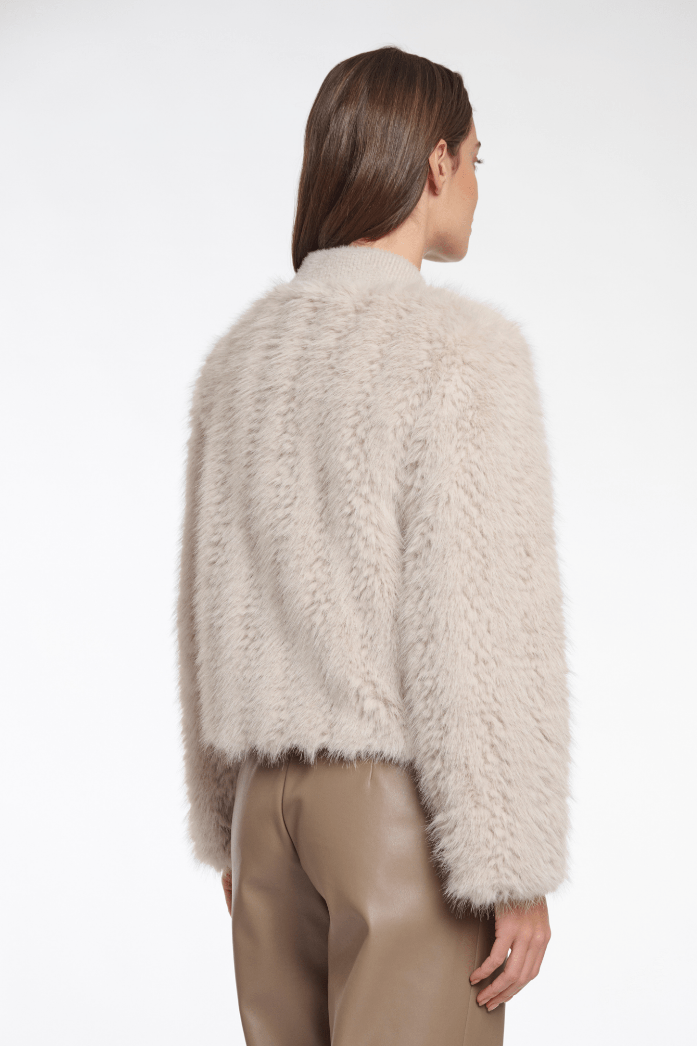 Person wearing a fluffy beige sweater on a white background