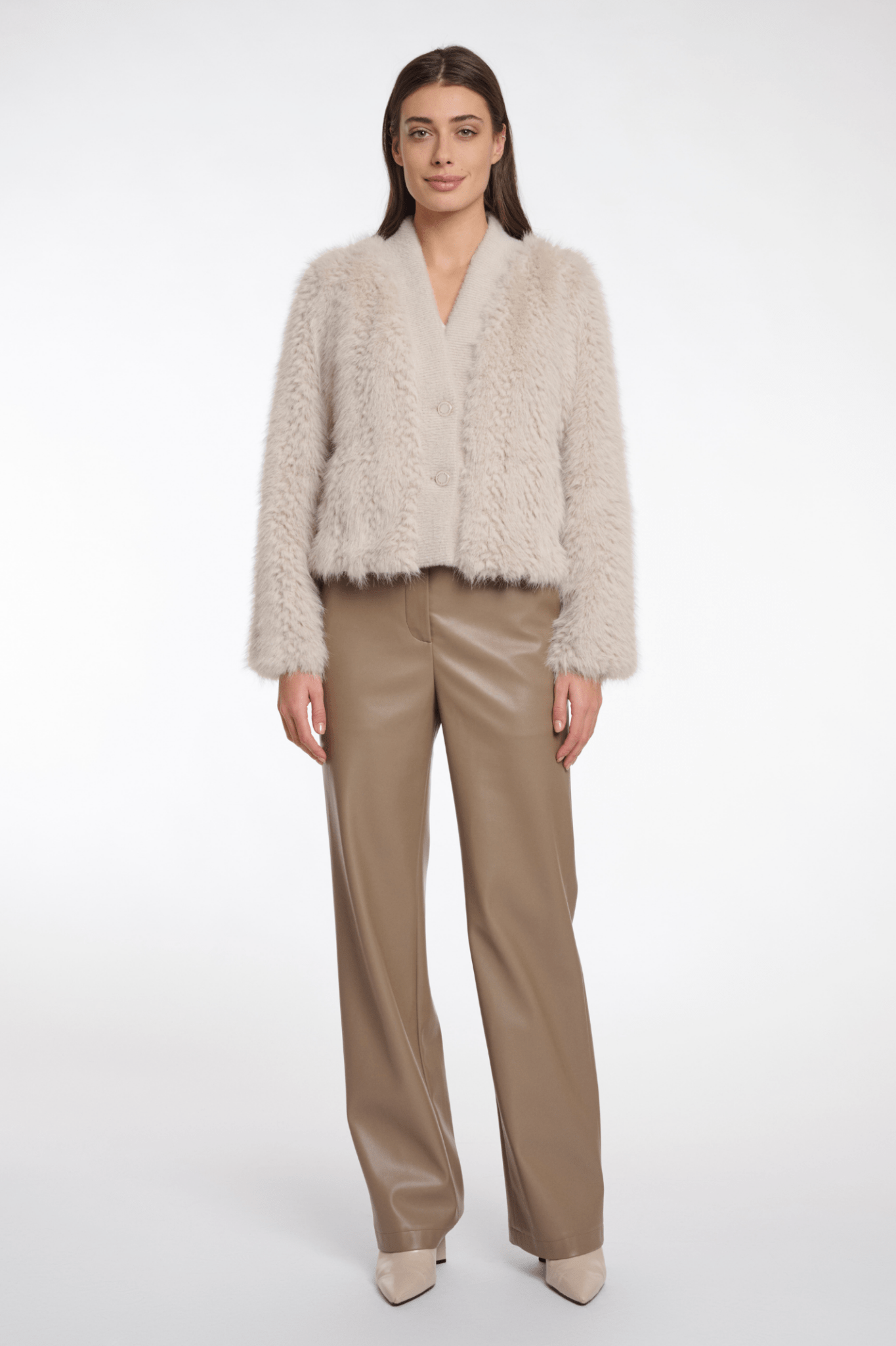Woman wearing a beige fur jacket and beige pants on a white background