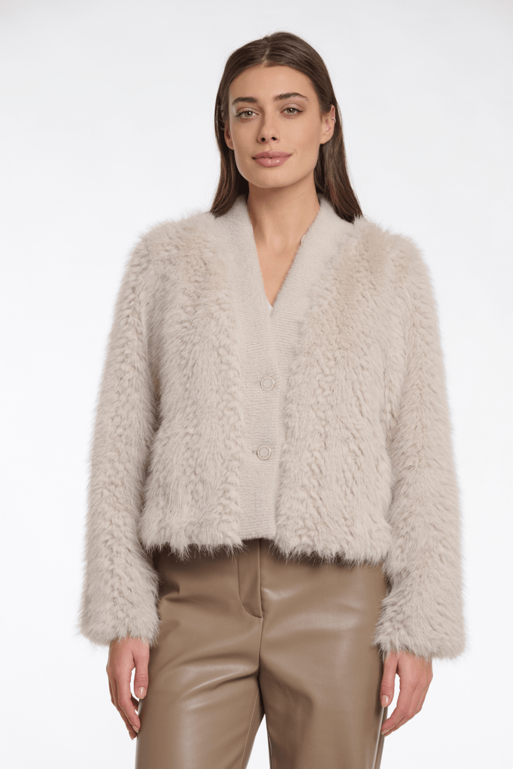 Woman wearing a beige fluffy jacket and beige pants on a white background