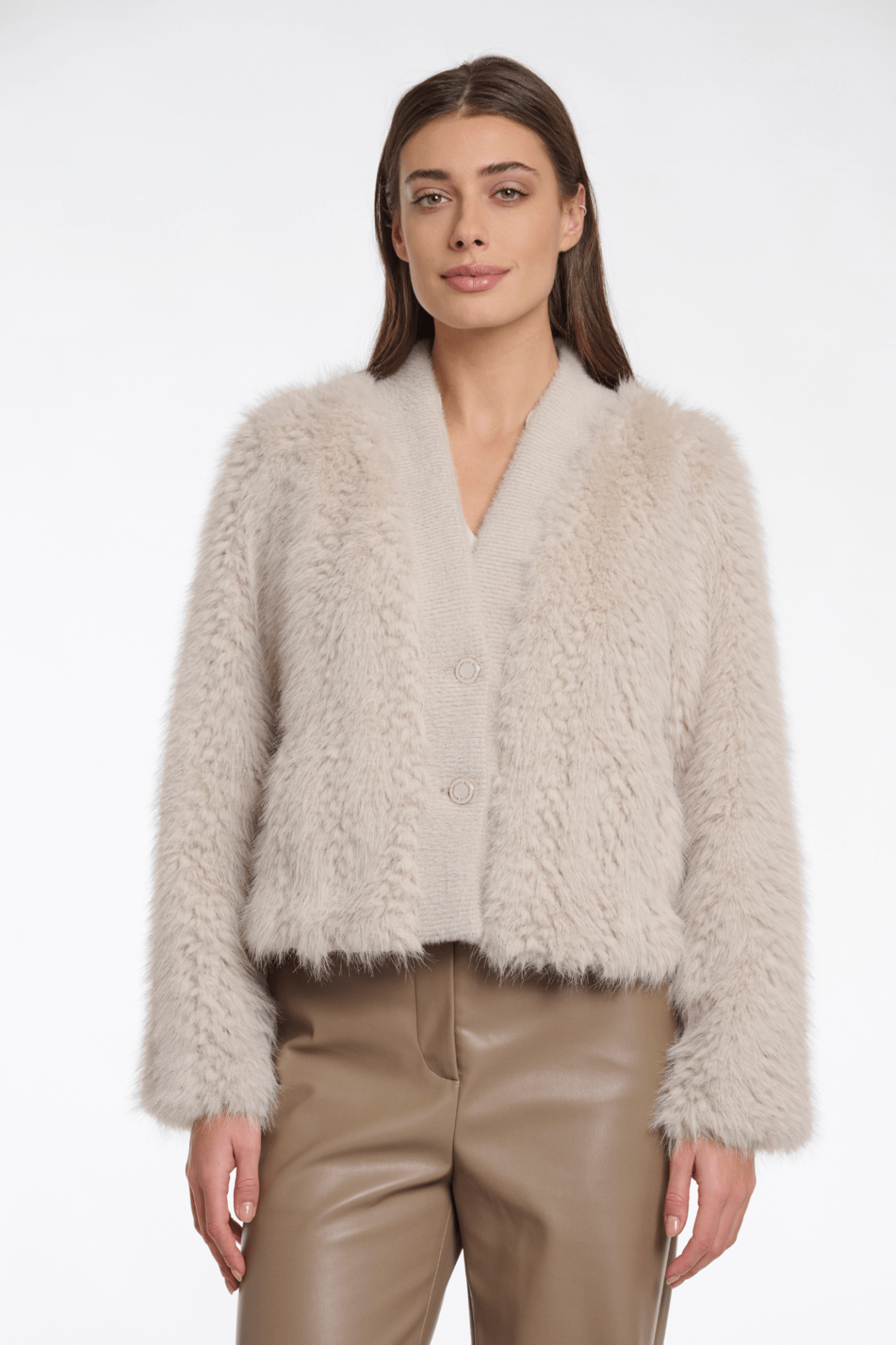 Woman wearing a beige fluffy jacket and beige pants on a white background