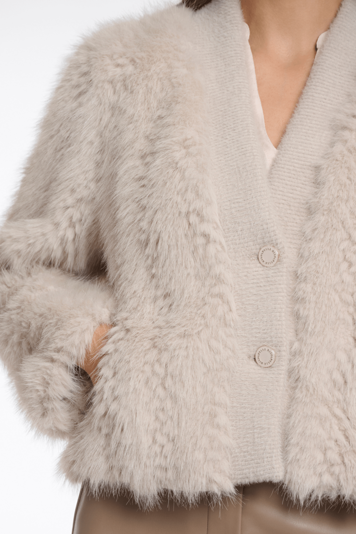 Close-up of a fluffy beige cardigan with buttons on a white background