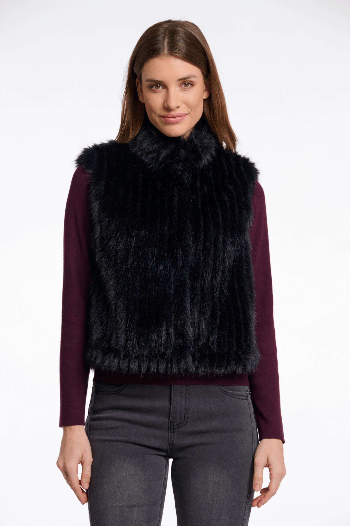 Woman wearing a black fur vest over a purple shirt on a white background