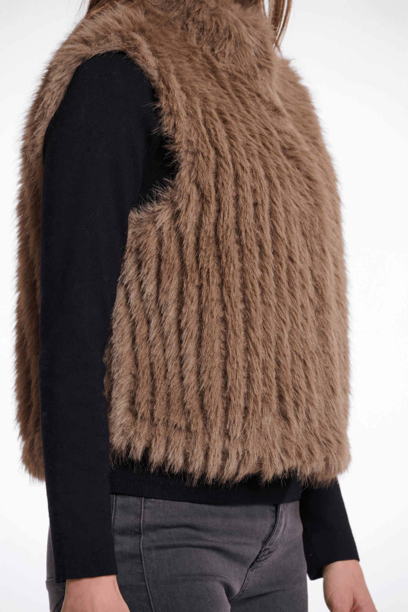 Brown fuzzy vest over a black shirt on a white background