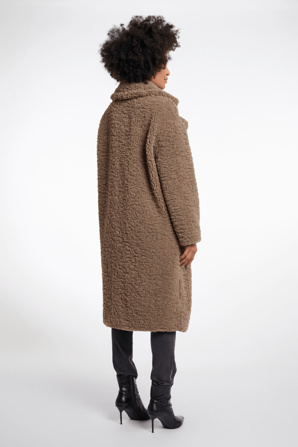 Person wearing a long brown coat on a white background
