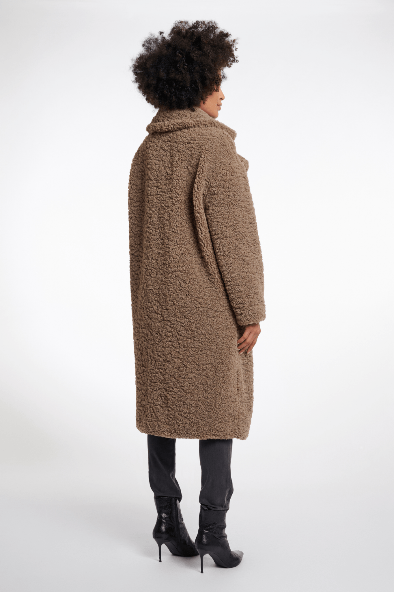 Person wearing a long brown coat on a white background