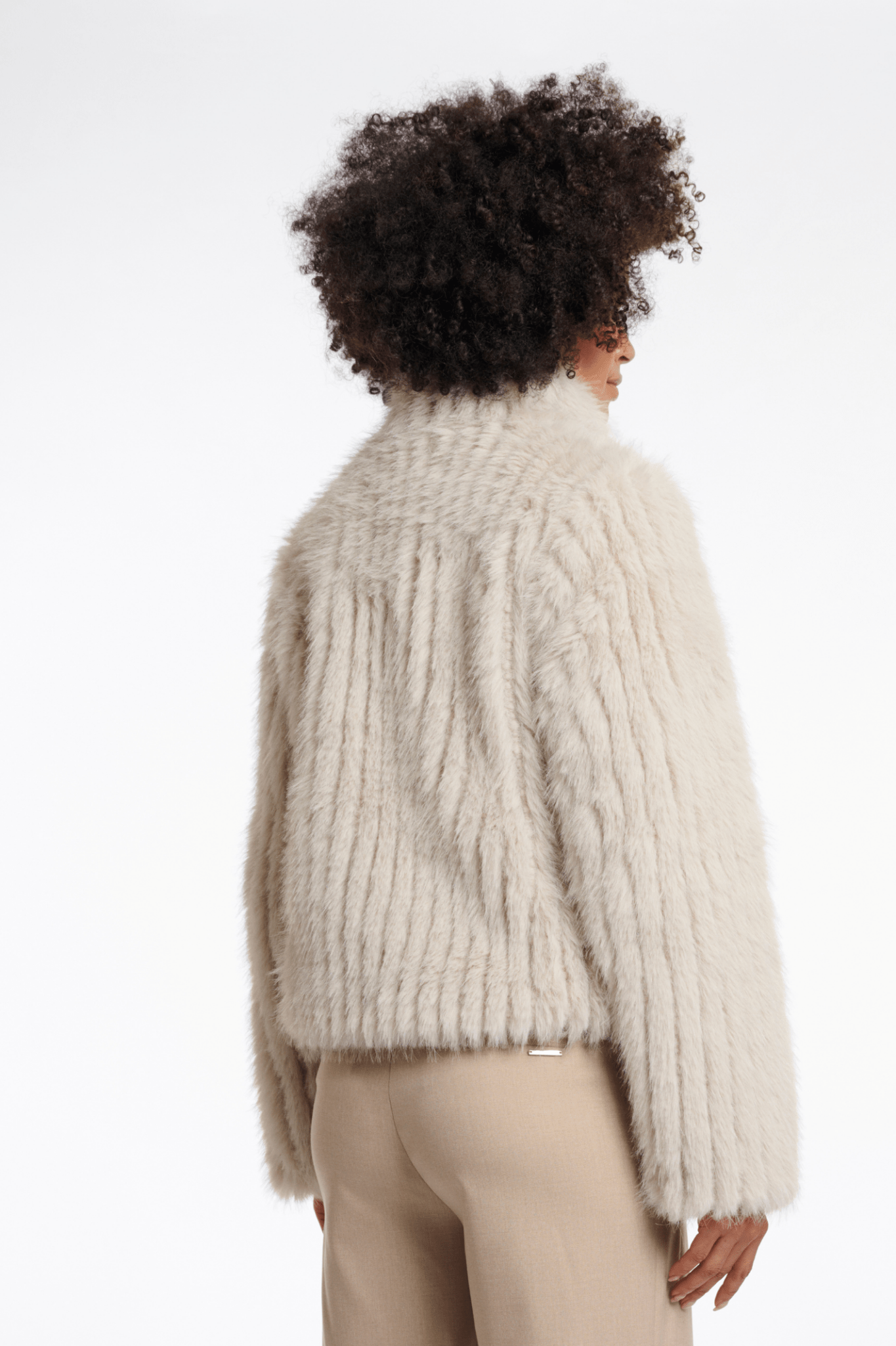 Person wearing a fluffy beige sweater on a plain background