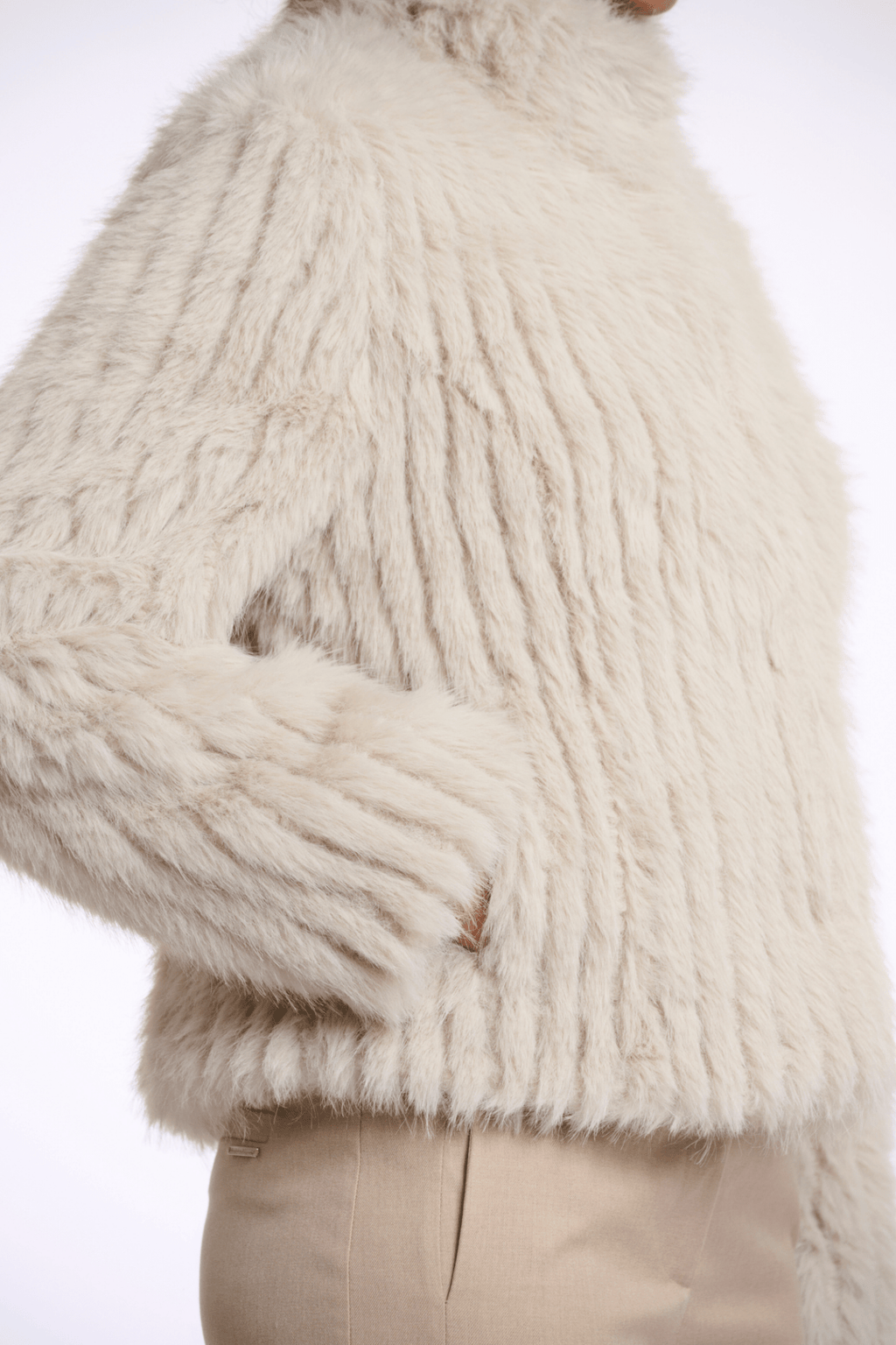 Close-up of a person wearing a fluffy white coat with a neutral background
