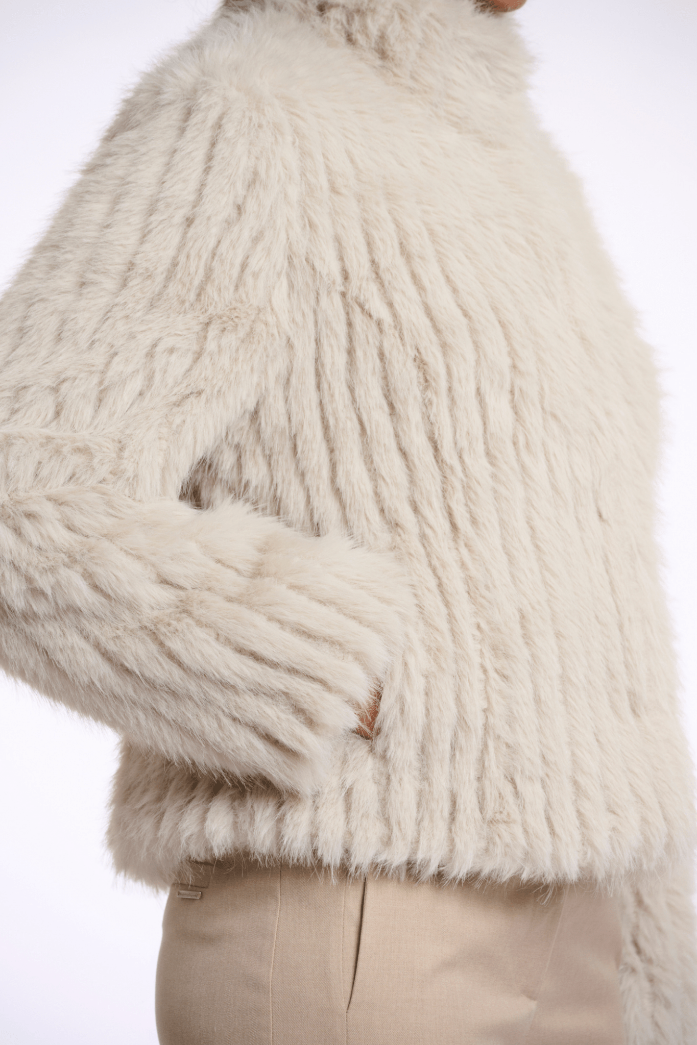 Close-up of a person wearing a fluffy white coat with a neutral background