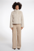 Woman wearing a beige ribbed sweater and beige pants on a white background